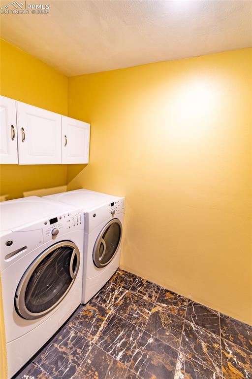 washroom featuring marble finish floor, washer and dryer, and cabinet space