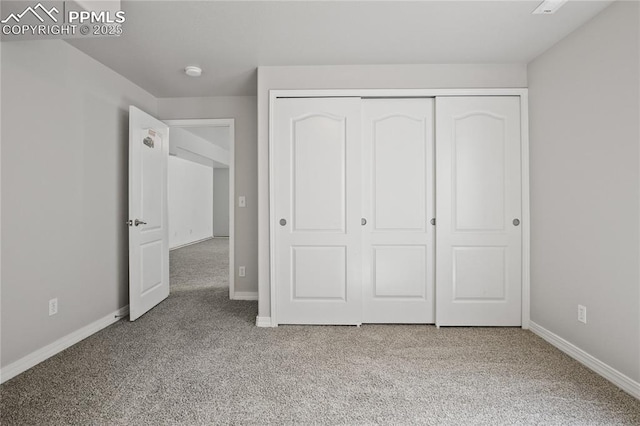 unfurnished bedroom with baseboards, carpet flooring, and a closet