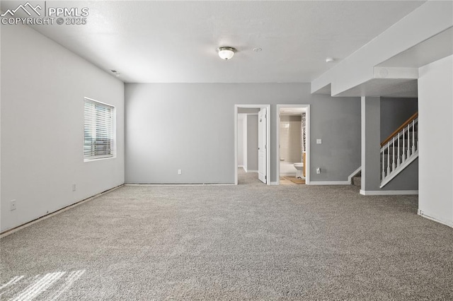 unfurnished room with baseboards, carpet, and stairway