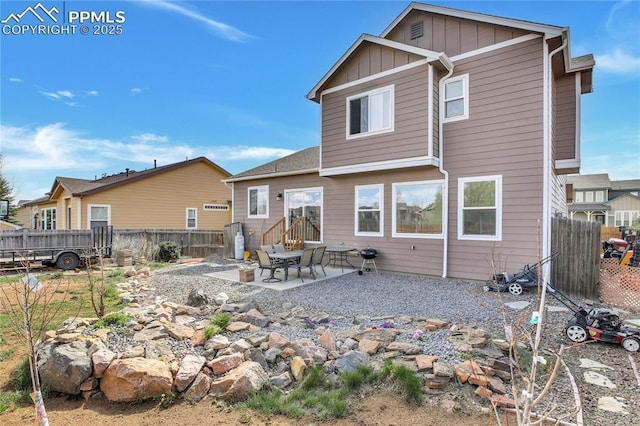 rear view of house with board and batten siding, fence, and a patio area