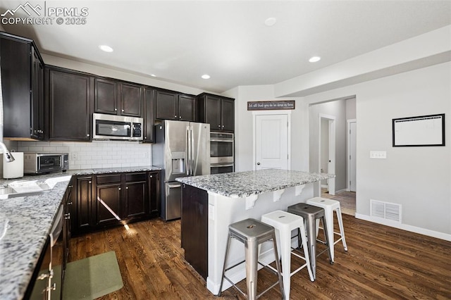 8040 Barraport Dr, Colorado Springs, CO 80908 - kitchen featuring dark wood finished floors, visible vents, backsplash, and appliances with stainless steel finishes