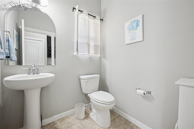 8040 Barraport Dr, Colorado Springs, CO 80908 - half bath featuring toilet, a sink, tile patterned floors, and baseboards
