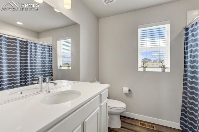 bathroom with toilet, visible vents, baseboards, wood finished floors, and vanity