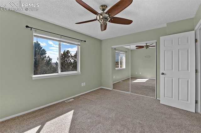 unfurnished bedroom with visible vents, a textured ceiling, a closet, carpet flooring, and baseboards