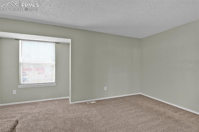 carpeted spare room featuring visible vents, a textured ceiling, and baseboards