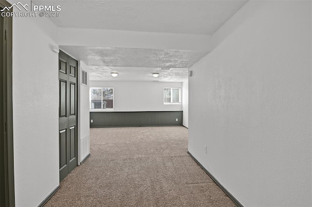empty room featuring a wealth of natural light, visible vents, carpet floors, and a textured ceiling