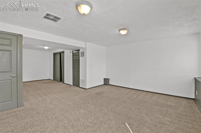 unfurnished room with carpet flooring, visible vents, and a textured ceiling