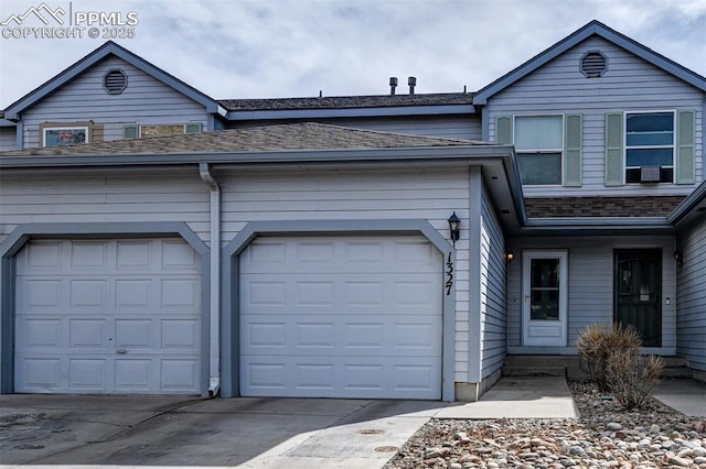 view of front of house with driveway, a garage, and roof with shingles