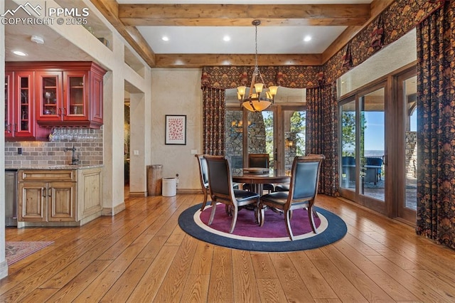 dining room with beamed ceiling, baseboards, light wood-style floors, a high ceiling, and an inviting chandelier