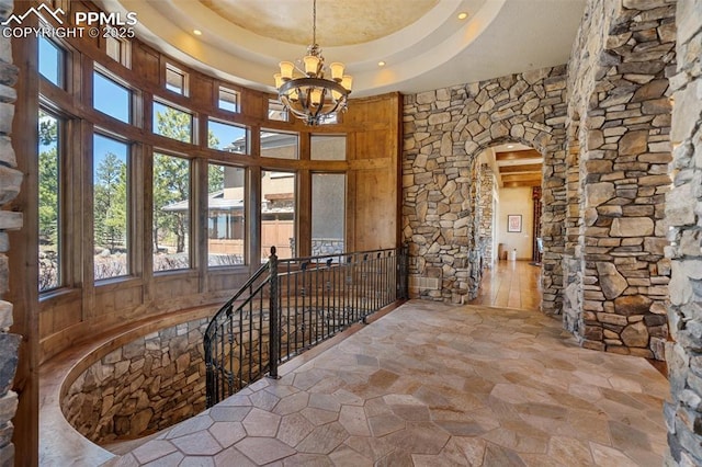 corridor with arched walkways, an upstairs landing, a chandelier, and plenty of natural light