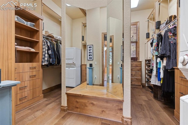 walk in closet with stacked washer and clothes dryer and wood finished floors