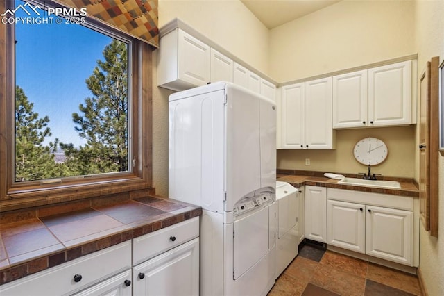 laundry area with washer / clothes dryer, cabinet space, a sink, and stone finish flooring