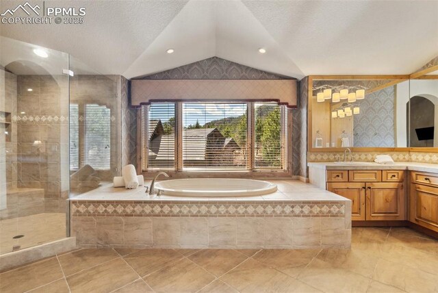 bathroom featuring vaulted ceiling, a tile shower, vanity, a textured ceiling, and a bath