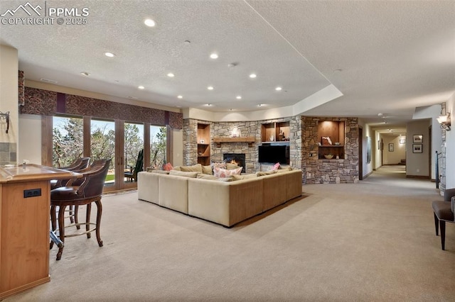 living area with a textured ceiling, indoor bar, recessed lighting, a stone fireplace, and light carpet
