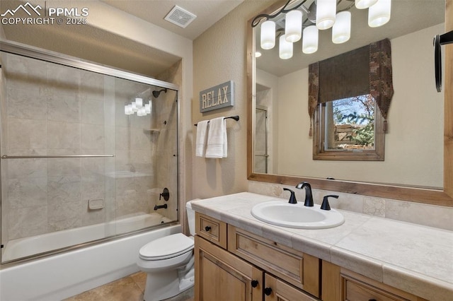 bathroom with toilet, vanity, bath / shower combo with glass door, tile patterned flooring, and visible vents