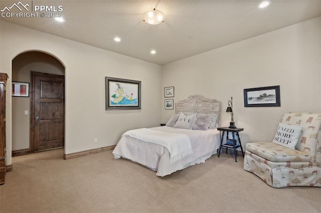 carpeted bedroom with arched walkways, a textured ceiling, baseboards, and recessed lighting