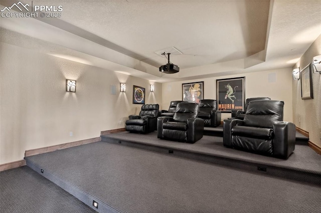 home theater room featuring carpet flooring, a tray ceiling, and baseboards