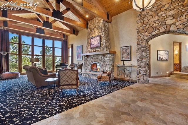 living area with high vaulted ceiling, wooden ceiling, beam ceiling, stone finish flooring, and a fireplace