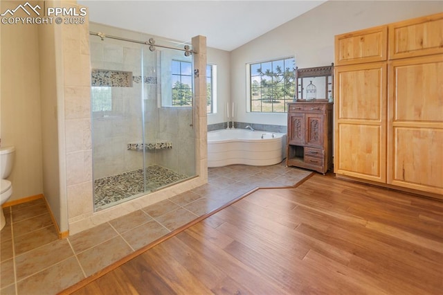 266 University Dr, Woodland Park, CO 80863 - bathroom featuring wood finished floors, lofted ceiling, a shower stall, a garden tub, and toilet