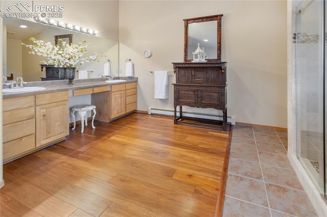 266 University Dr, Woodland Park, CO 80863 - bathroom with double vanity, wood finished floors, a baseboard heating unit, and a sink