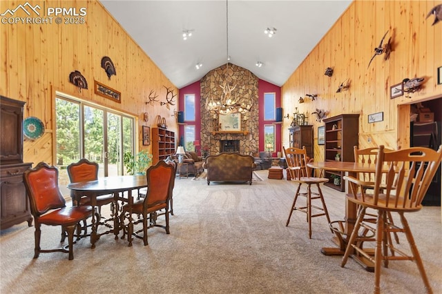 266 University Dr, Woodland Park, CO 80863 - dining space with wooden walls, carpet, a stone fireplace, and high vaulted ceiling