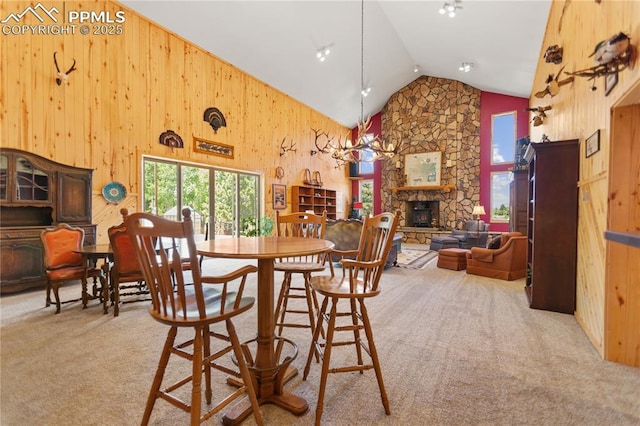 266 University Dr, Woodland Park, CO 80863 - dining space featuring wooden walls, a fireplace, carpet floors, and high vaulted ceiling