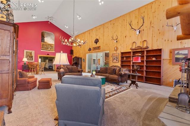 266 University Dr, Woodland Park, CO 80863 - carpeted living room featuring high vaulted ceiling, an inviting chandelier, and wooden walls
