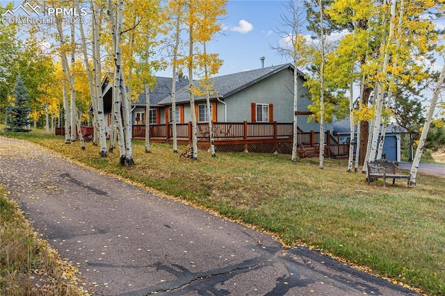 266 University Dr, Woodland Park, CO 80863 - view of front of house featuring a deck, a shingled roof, and a front lawn