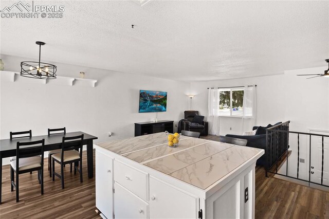 kitchen featuring tile countertops, a textured ceiling, dark wood finished floors, open floor plan, and white cabinetry