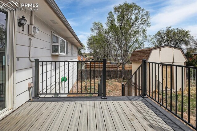 wooden deck with an outdoor structure, a fenced backyard, and a storage unit