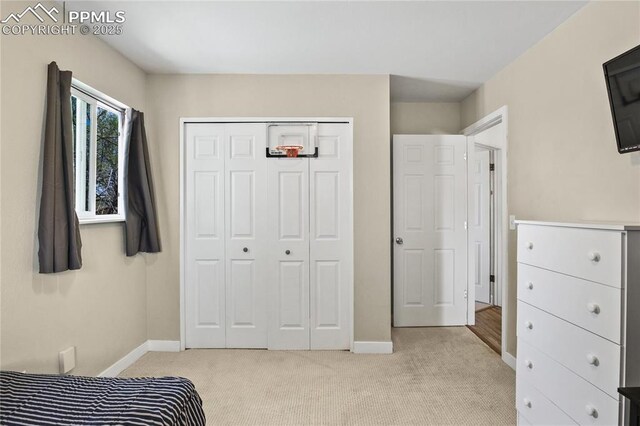 bedroom featuring baseboards, a closet, and light carpet