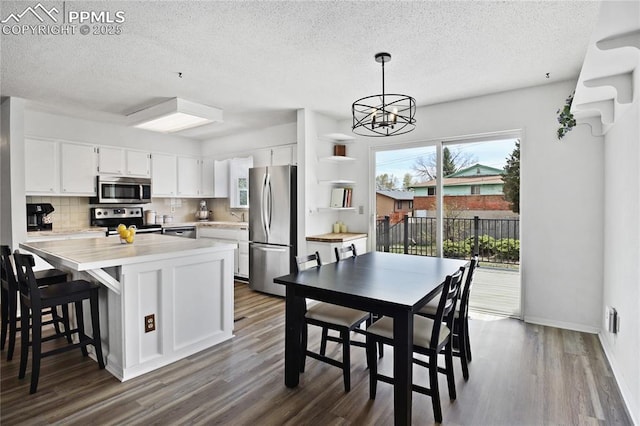 kitchen featuring light countertops, stainless steel appliances, a textured ceiling, and dark wood-type flooring