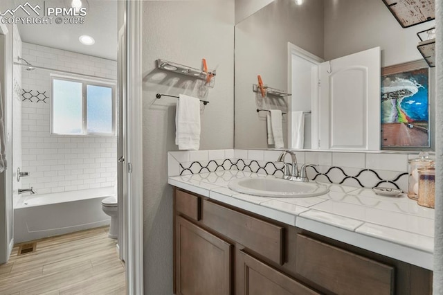 5409 Haes Haven Vw, Colorado Springs, CO 80908 - full bath featuring toilet, backsplash, vanity, wood finished floors, and tub / shower combination