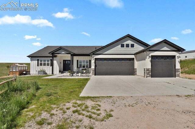 5409 Haes Haven Vw, Colorado Springs, CO 80908 - view of front of home featuring stone siding, an attached garage, concrete driveway, a front yard, and board and batten siding