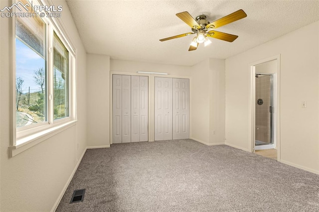 unfurnished bedroom with visible vents, two closets, a textured ceiling, carpet floors, and baseboards