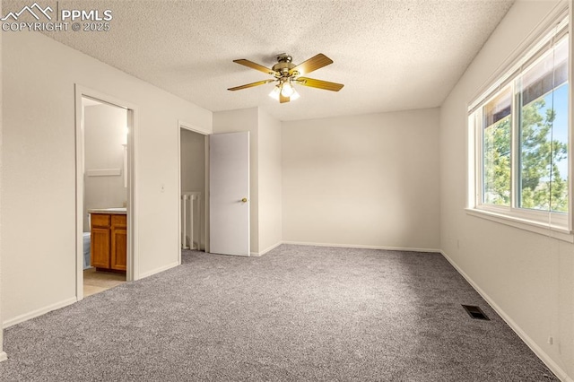 unfurnished bedroom featuring visible vents, baseboards, light colored carpet, ensuite bath, and a textured ceiling