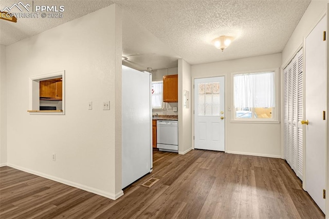 interior space with white appliances, baseboards, dark wood-style flooring, and a textured ceiling