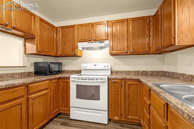 kitchen with under cabinet range hood, white range with electric stovetop, brown cabinets, and black microwave