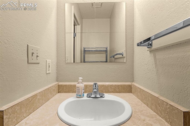 bathroom featuring a textured wall and a sink