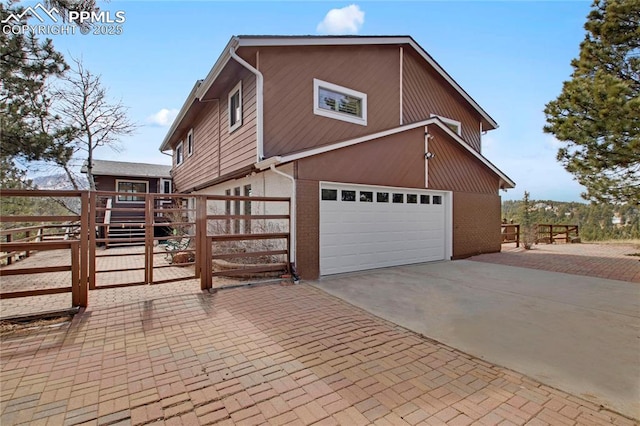 view of home's exterior featuring a garage, decorative driveway, brick siding, and fence