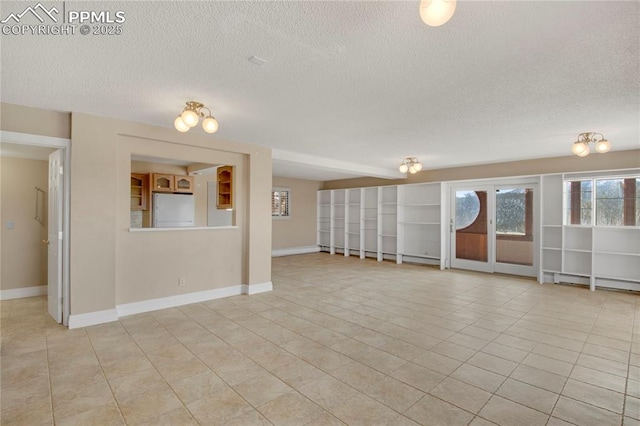 unfurnished living room with a textured ceiling, light tile patterned floors, and baseboards
