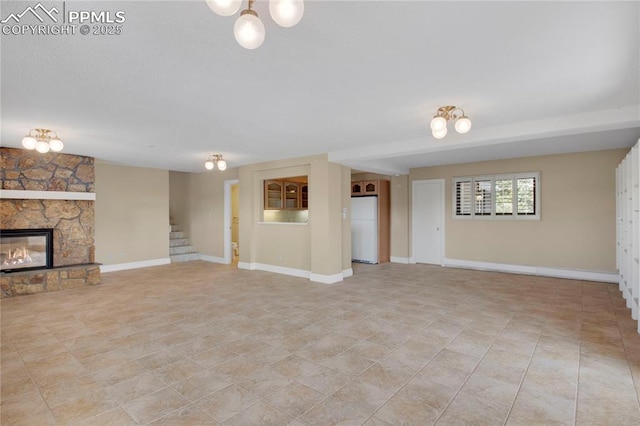 unfurnished living room featuring an inviting chandelier, light tile patterned flooring, stairs, a stone fireplace, and baseboards