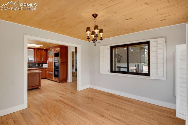 unfurnished dining area with a chandelier, light wood-type flooring, baseboards, and wooden ceiling