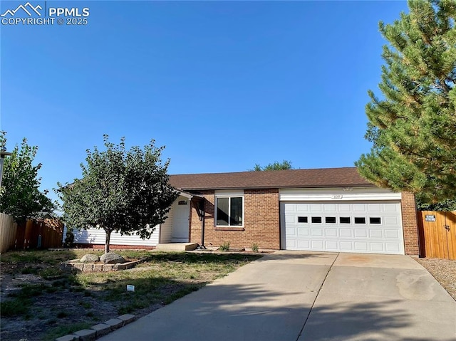 single story home with fence, an attached garage, concrete driveway, brick siding, and a shingled roof