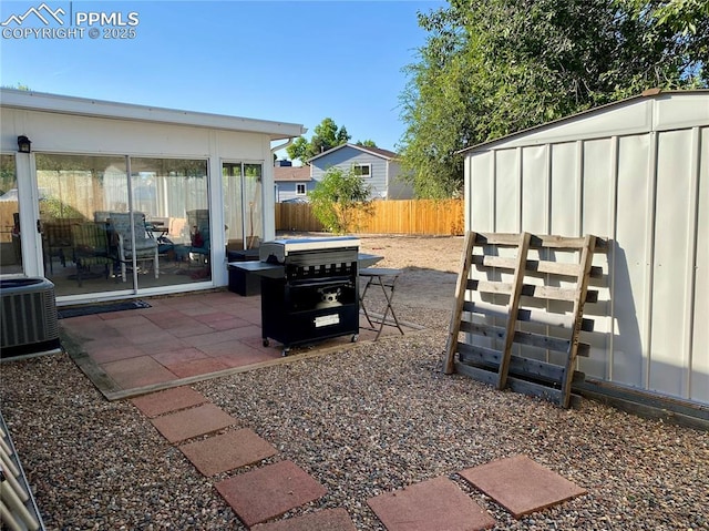 view of patio / terrace featuring a shed, an outbuilding, central AC, and fence