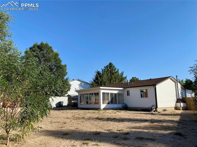 rear view of house with a sunroom, crawl space, and fence