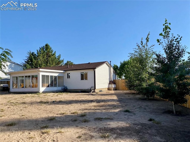 rear view of house featuring a sunroom and fence