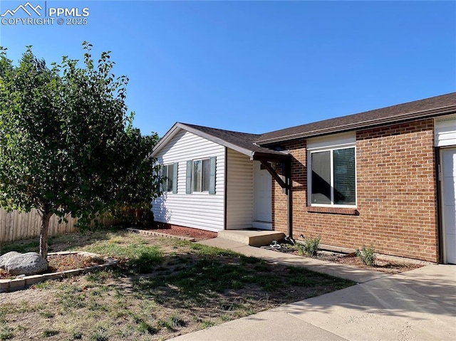 exterior space featuring brick siding and fence