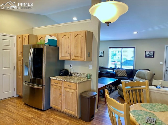 kitchen with vaulted ceiling, light wood-style floors, stainless steel fridge, and light brown cabinets