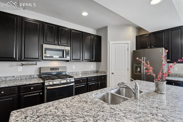 1632 Derbyshire St, Colorado Springs, CO 80910 - kitchen featuring recessed lighting, dark cabinetry, stainless steel appliances, a sink, and light stone counters